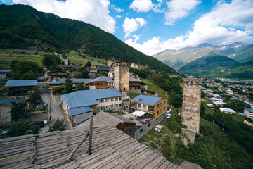 Fototapeta na wymiar Svan towers in Mestia village with summer mountain. Roofs an buidings. Travel place Georgia