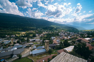 Fototapeta na wymiar Svan towers in Mestia village with summer mountain. Roofs an buidings. Travel place Georgia