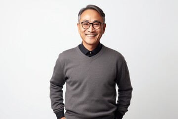 Fototapeta premium Portrait of happy mature Asian man in eyeglasses standing over white background