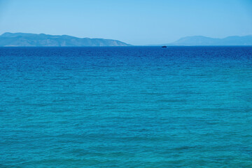 Ship sails in vast Mediterranean sea under Greek blue sky background. Summer destination, space.