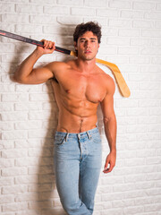 Handsome young man shirtless with hockey stick in hands - 636705830
