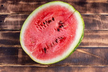 Half of a juicy, ripe watermelon on a wood background. Half of a watermelon on a cutting board close up