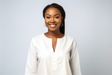 Lifestyle portrait of a Nigerian woman in her 20s in a white background wearing a simple tunic - obrazy, fototapety, plakaty