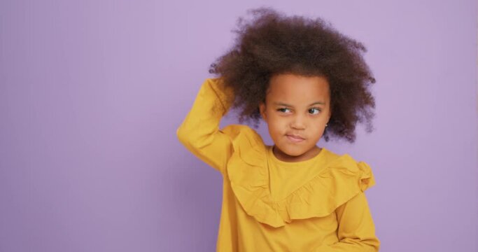 cute black pensive little girl kid pointing finger up with open mouth, cratching head, having idea, showing inspiration motivation gesture, problem solution isolated purple background Eureka, plan