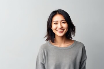 Portrait of a smiling young asian woman standing over gray background