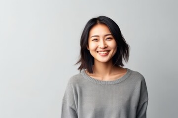 Obraz premium Portrait of a smiling young asian woman standing over gray background