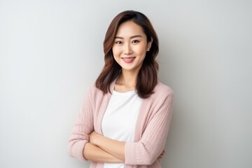 Fototapeta premium Medium shot portrait of a Chinese woman in her 30s in a minimalist or empty room background wearing a chic cardigan