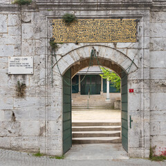 Arched entrance with open green metal door in brick stone wall leading to 17th century Cinili Mosque in Uskudar, Istanbul, Turkey