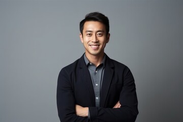 Portrait of a smiling young asian business man, isolated on gray background