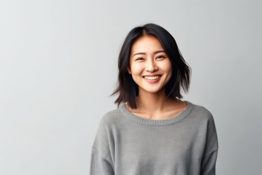 Portrait Of A Smiling Young Asian Woman Standing Over Gray Background