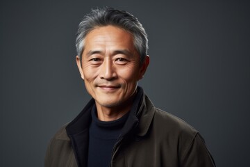 Portrait of a happy asian man looking at camera isolated on grey background