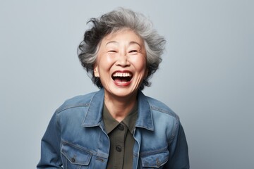 Obraz na płótnie Canvas Happy asian senior woman laughing and looking at camera isolated on grey background