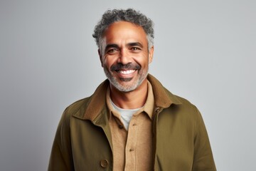 Obraz premium Portrait of a mature Indian man smiling at the camera while standing against grey background