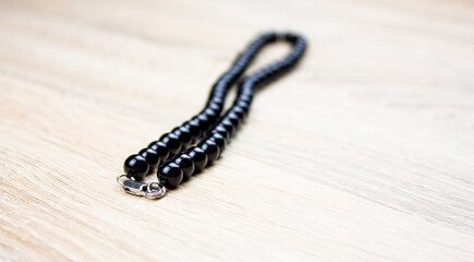 Black beads on a light background. Black necklace with round beads. Jewelry made of natural stones.