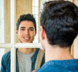 Photo of a man contemplating his reflection in the mirror