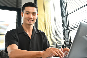 Portrait image of Smart Young adult businessman working with a laptop in the office.