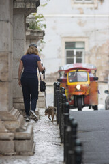 Fototapeta na wymiar A woman walks a dog on an old european street