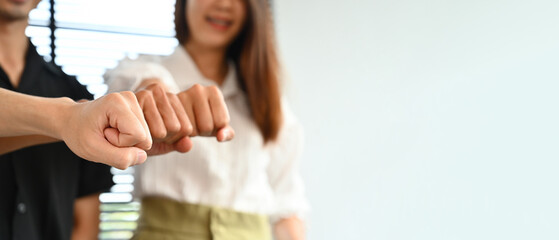 Close-up image of a group of mix aged creative workers bumping fists together, co-working, and unity concept, Ready to hit every problem.