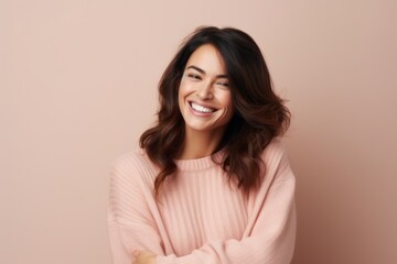 Fototapeta premium Portrait of a smiling young woman looking at camera isolated over beige background
