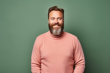 Fototapeta premium smiling middle aged man in pink sweater looking at camera isolated on green