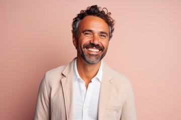 Obraz premium Portrait of a handsome middle-aged Hispanic man in a beige jacket on a pink background