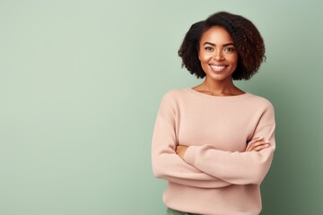 Fototapeta premium Portrait of a smiling african american woman standing with arms crossed over green background
