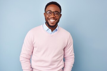 Fototapeta premium Medium shot portrait of a Nigerian man in his 30s in a pastel or soft colors background wearing a chic cardigan