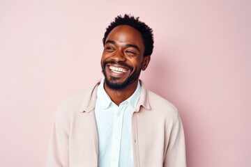 Fototapeta premium Medium shot portrait of a Nigerian man in his 30s in a pastel or soft colors background wearing a chic cardigan