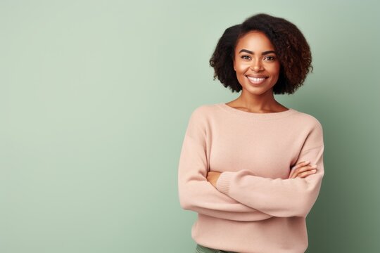 Portrait of a smiling african american woman standing with arms crossed over green background