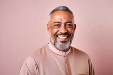 Obraz premium Portrait of a happy Indian man smiling at the camera on a pink background