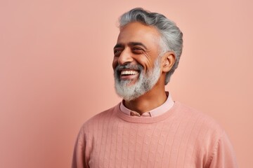Obraz premium Portrait of happy Indian man looking at camera and laughing while standing against pink background