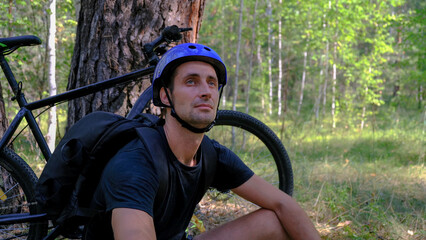 mountain bike.An active lifestyle.A cyclist in a helmet and with a backpack stopped in the forest...