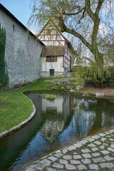 Obraz premium section of the medieval outer wall of the town of Wangen i.A. (Germany) with a water course in which a house is reflected
