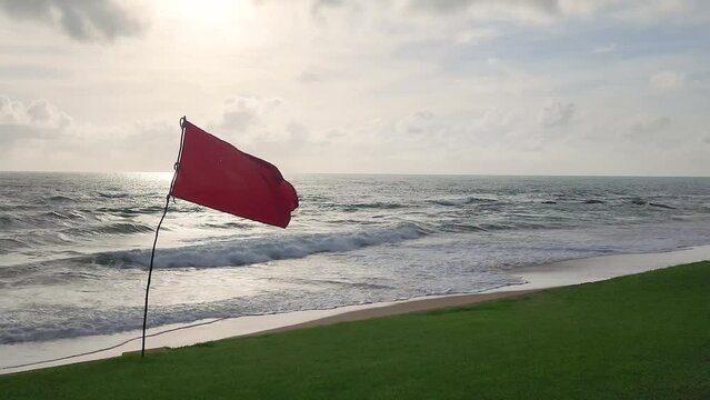 A red flag with heavy windy condition, it is the bad weather warning sign, do not swimming in the sea. Safety sign and symbol 4k footage in the nature landscape.