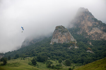 Beautiful mountain landscape with rocks, fog and paragliders - 636721078