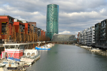 30-story skyscraper Westhafen Tower in Gutleitviertel district, buildings on river Main shore, boats, yachts moored on banks, concept tourism, independence day, Frankfurt, Germany - February 26, 2023