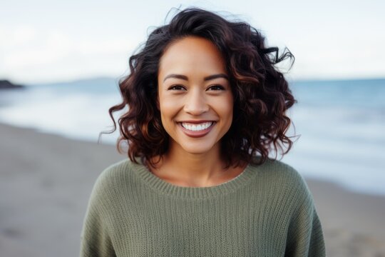 Lifestyle portrait of a Indonesian woman in her 30s in a beach background wearing a cozy sweater