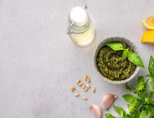 Fototapeta na wymiar Traditional Italian pesto in a bowl with green basil, pine nuts and olive oil on a light background. A classic sauce for spaghetti or bruschetta. Delicious vegetarian homemade food.
