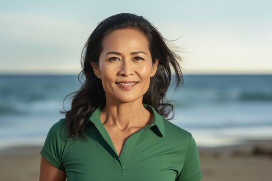 Lifestyle portrait of a Indonesian woman in her 40s in a beach background wearing a sporty polo shirt