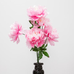 Artificial flowers in a black vase. Close up. On a white background