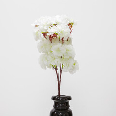 Artificial flowers in a black vase. Close up. On a white background