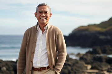 Lifestyle portrait of a Indonesian man in his 50s in a beach background wearing a chic cardigan