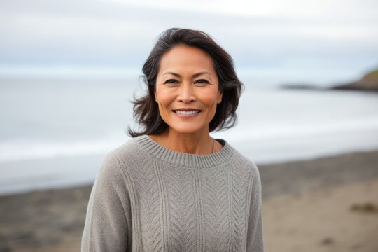 Lifestyle portrait of a Indonesian woman in her 50s in a beach background wearing a cozy sweater