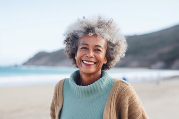 Medium shot portrait of a Brazilian woman in her 70s in a beach background wearing a cozy sweater