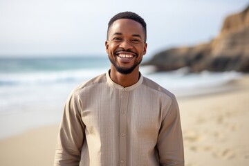 Lifestyle portrait of a Nigerian man in his 30s in a beach background wearing a chic cardigan