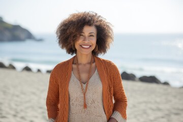 Lifestyle portrait of a Nigerian woman in her 40s in a beach background wearing a chic cardigan