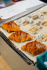 Freshly baked golden crispy croissants viewed from above sitting on a bakers tray fresh from the oven