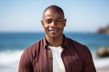 Lifestyle portrait of a Nigerian man in his 40s in a beach background wearing a chic cardigan