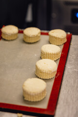 Freshly cut scone rounds sit on tray in professional bakers kitchen waiting to be baked
