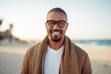 Portrait of happy african american man in eyeglasses smiling at camera on beach